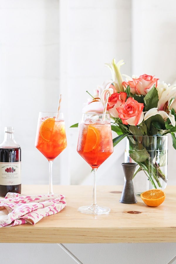 Aperol spritz with flowers, syrup and bar tools.