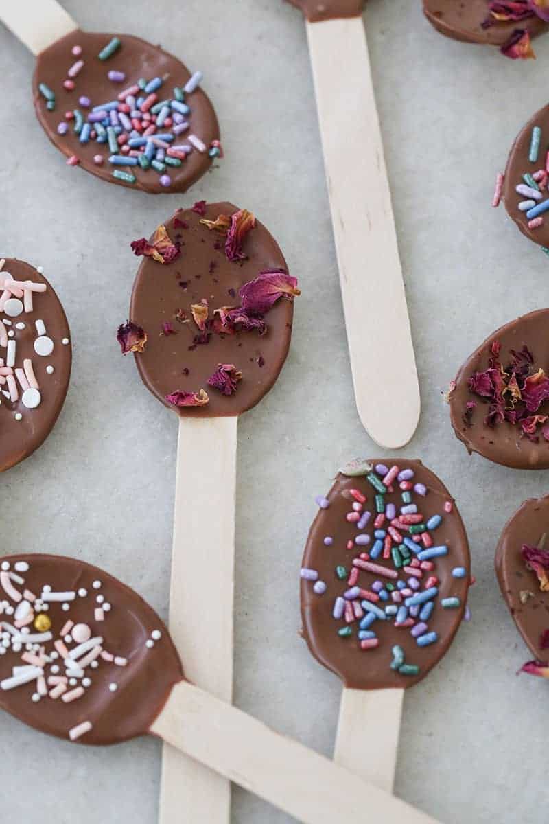 Wooden spoons dipped in chocolate with sprinkles and dried flowers. 