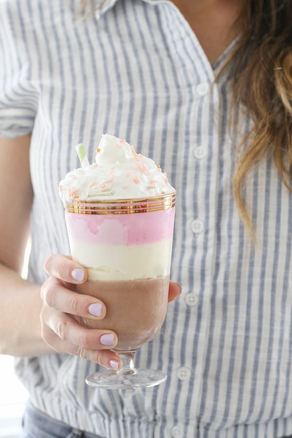 Girl holding a layered Neapolitan ice cream shake 