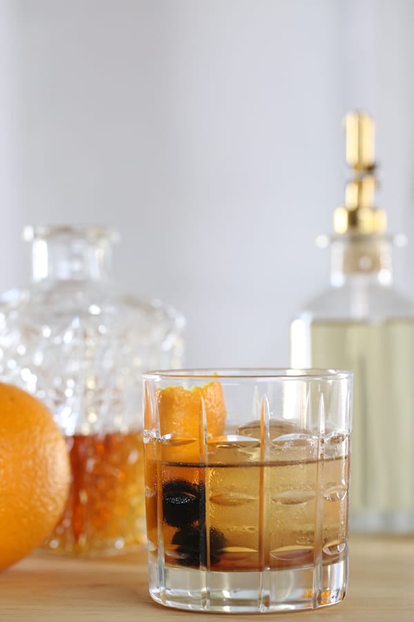 Old fashioned cocktail in a glass with two cherries and an orange rind. - rye whiskey, angostura bitters, bourbon or rye whiskey, maple syrup, whiskey cocktails, large ice cubes, how much a nutrient, food serving contributes