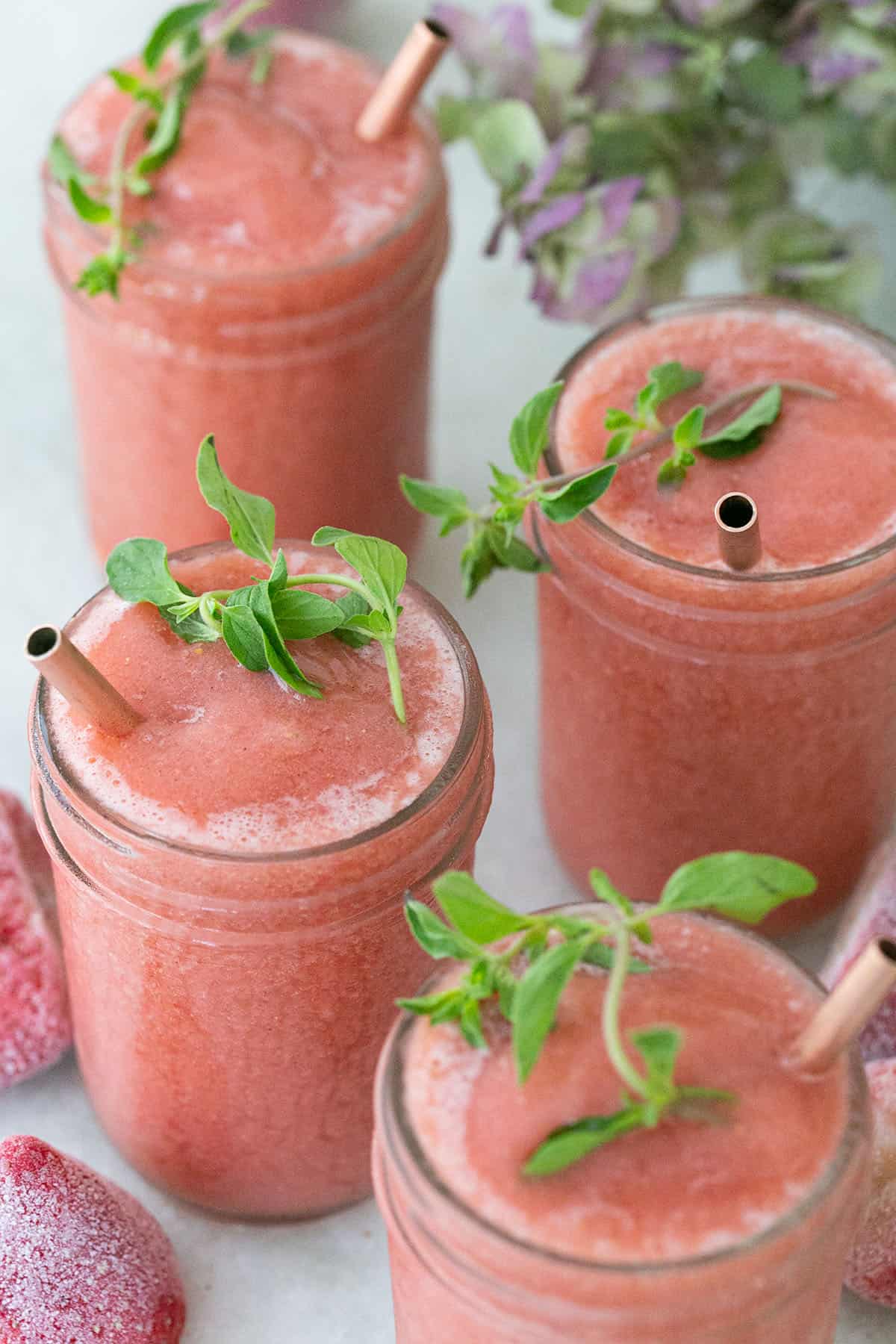 Strawberry frosé in glass jars with fresh herbs.