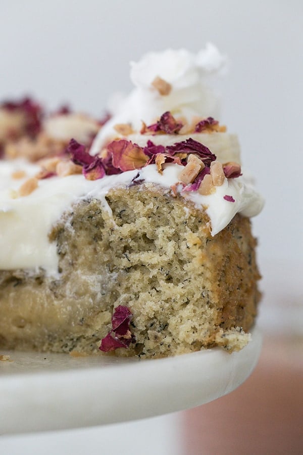 Slice of cake on a cake platter. - baking powder, banana bread, easy banana cake recipe, mashed banana, moist banana cake, dark chocolate chips, olive oil, baking powder