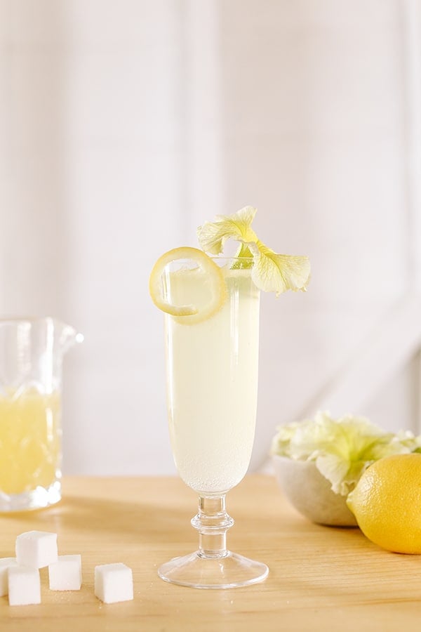 French 75 Cocktail in a flute with a lemon rind and a flower.