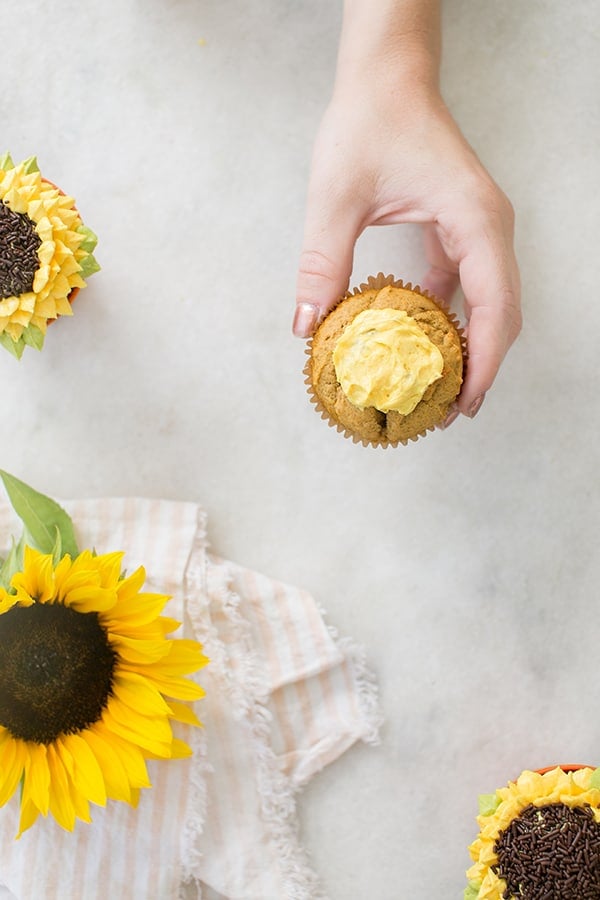 Hand holding a cupcake with a yellow frosting circle 