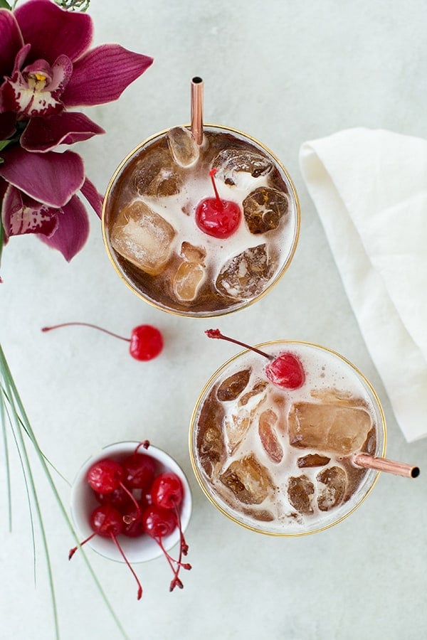 coffee tonic recipe with a cherry over the top on a marble table. 