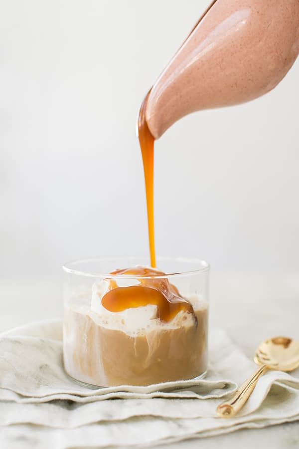 Caramel being poured into a glass of vanilla ice cream and coffee.