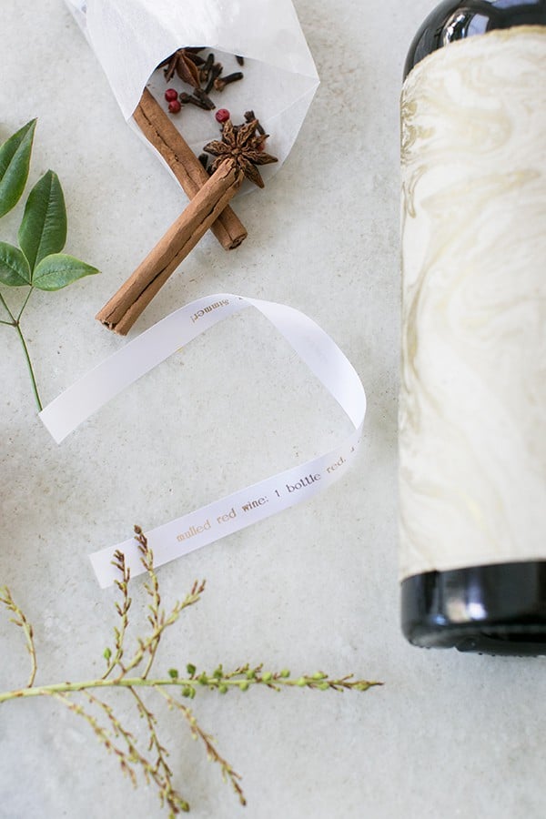 Ribbon, wine, cinnamon sticks on a marble table.