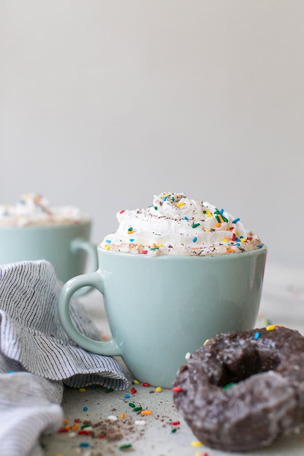 Hot chocolate coffee with whipped cream and sprinkles in a blue coffee mug. 