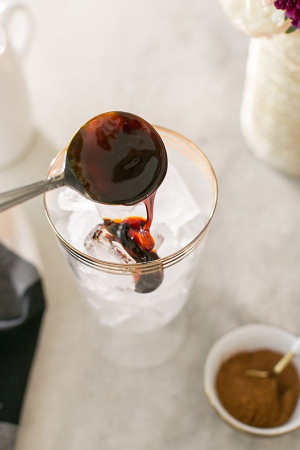 Molasses dripping in glass filled with ice. 