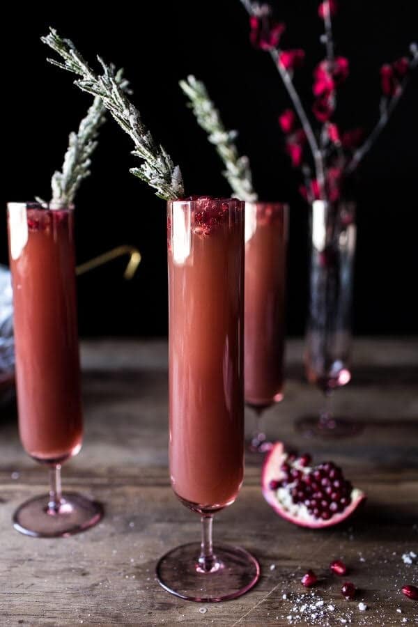 Pomegranate punch in tall glass on dark table with fresh pomegranate