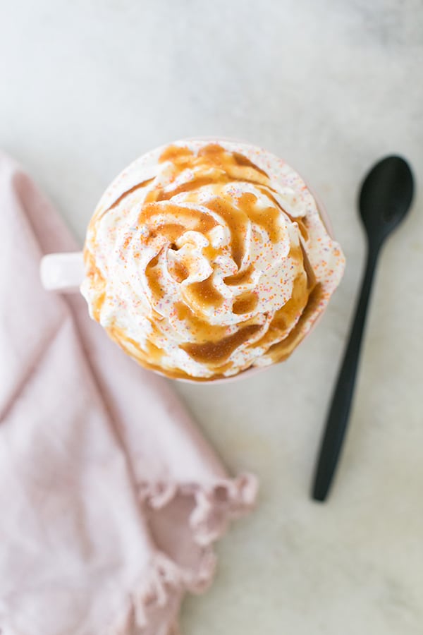 top down shot of creme brûlée coffee with whipped cream, in a white mug 