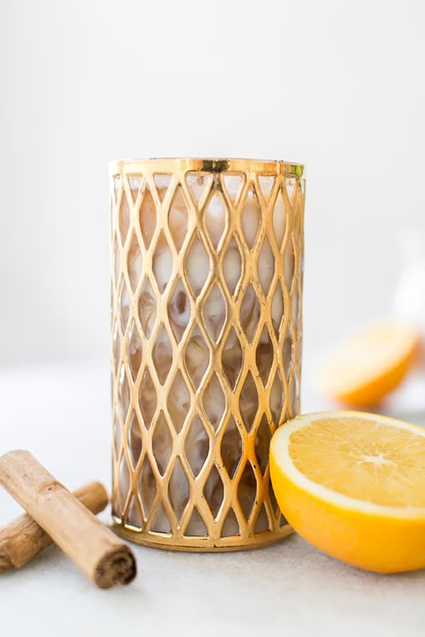 Cold brew coffee in a gold glass with cream and cinnamon.