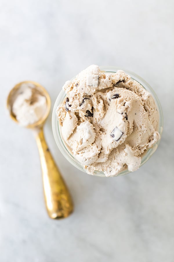 Coffee ice cream with chocolate chunks and a gold ice cream scooper.