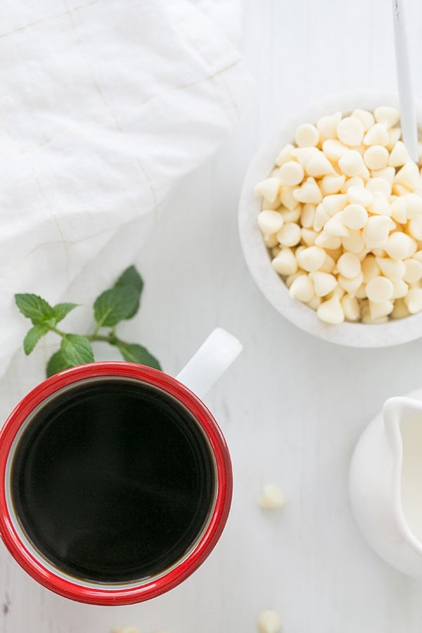 cup of brewed coffee with white chocolate chips next to it.