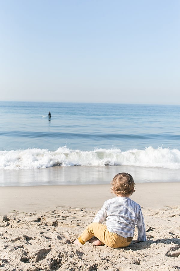 Baby watching a surfer on the beach in Santa Monica 