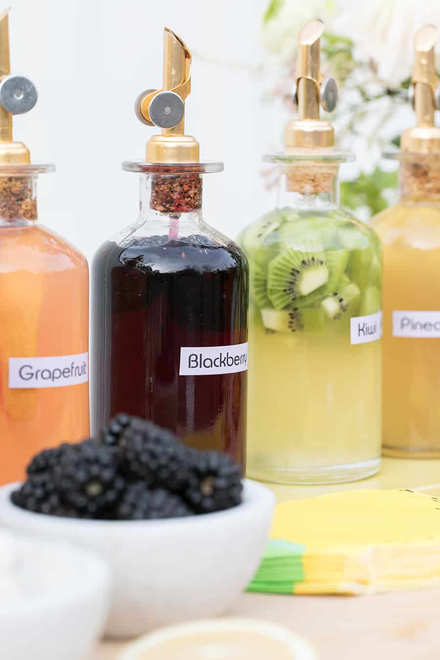 Homemade syrups in glasses with gold spouts.