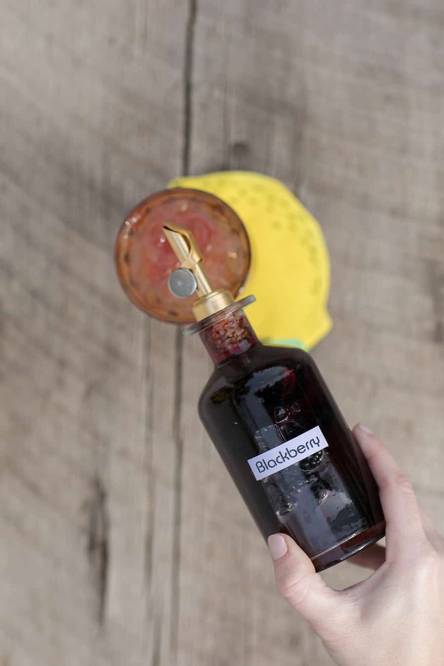 Pouring blackberry syrup in a glass.