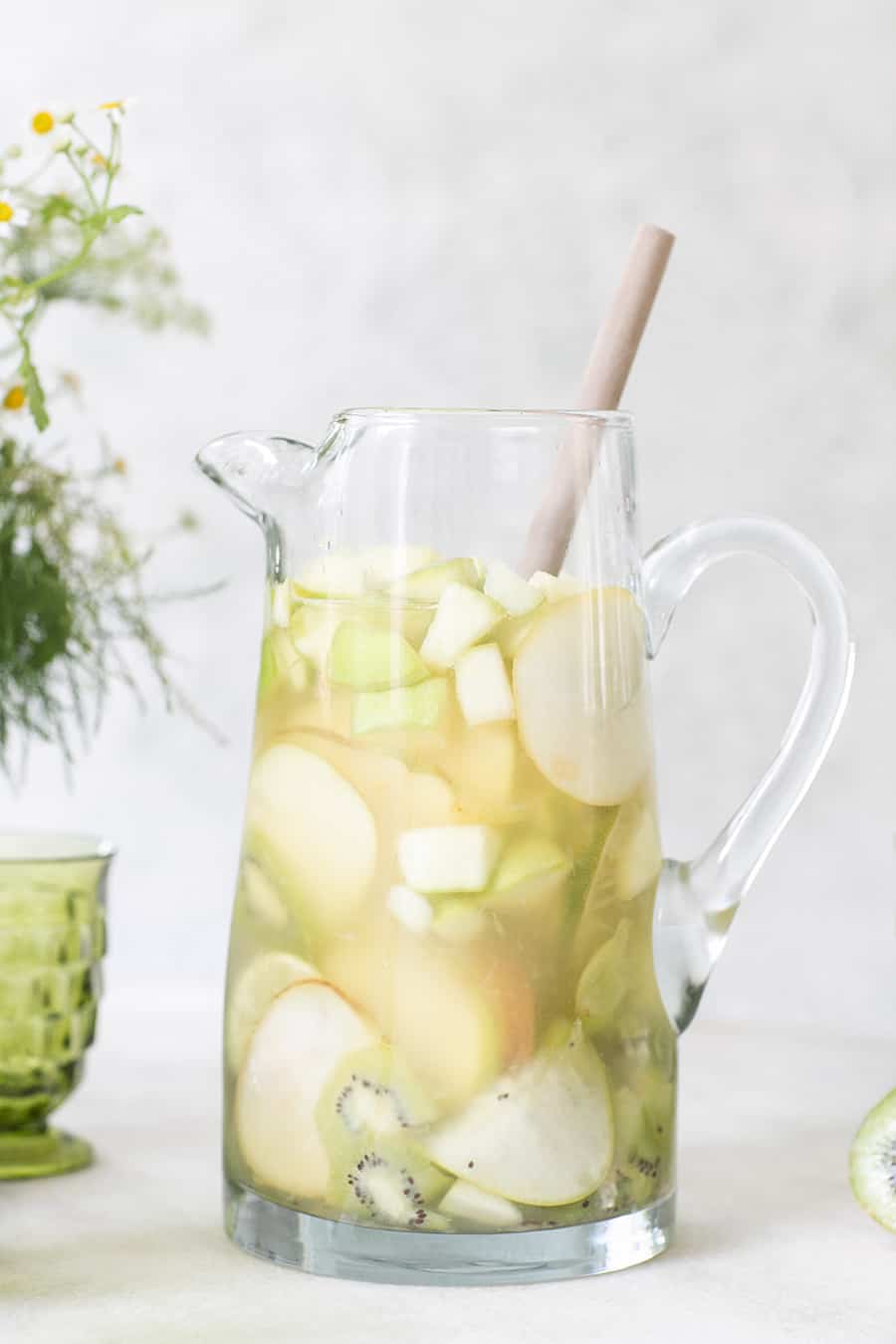 Green Irish Whiskey Sangria in a tall pitcher with sliced green fruit. 