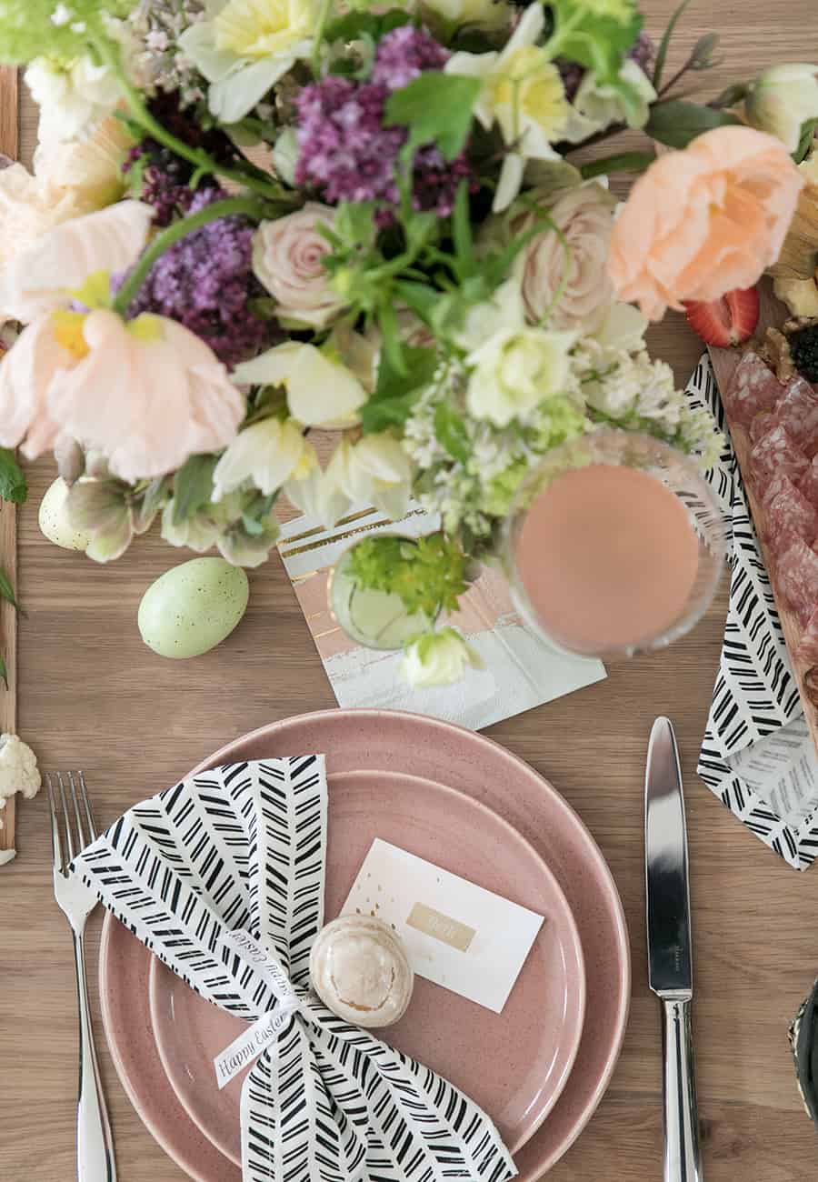 Easter table setting with pink plates with black napkin and easter egg.