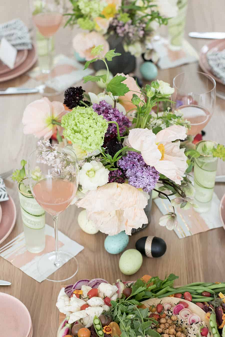 Easter brunch flowers on a table with a glass of rose and Easter eggs.