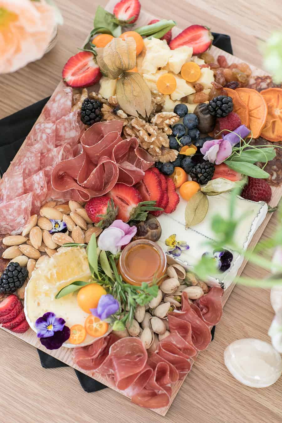 Charcuterie platter with fruit, cheese, nuts, almonds, meat and strawberries