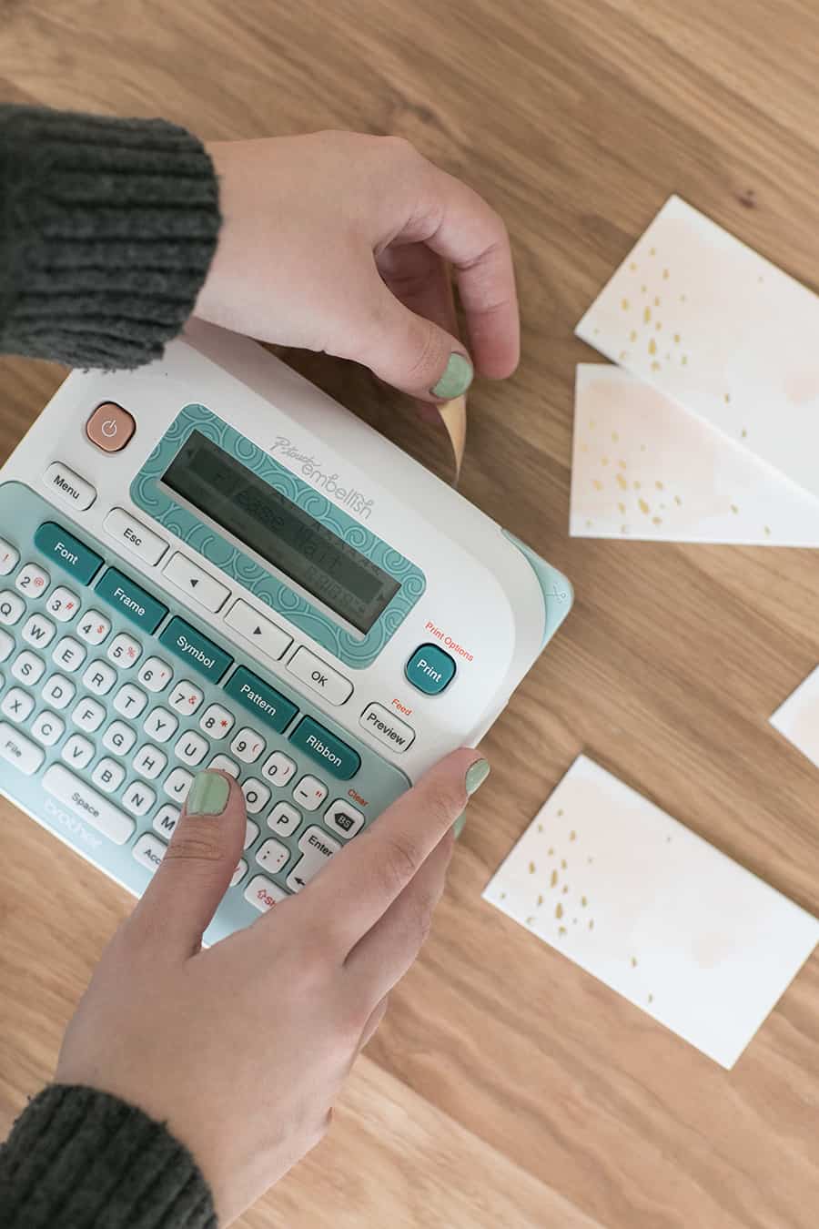 Hands using a P-touch embellish machine 