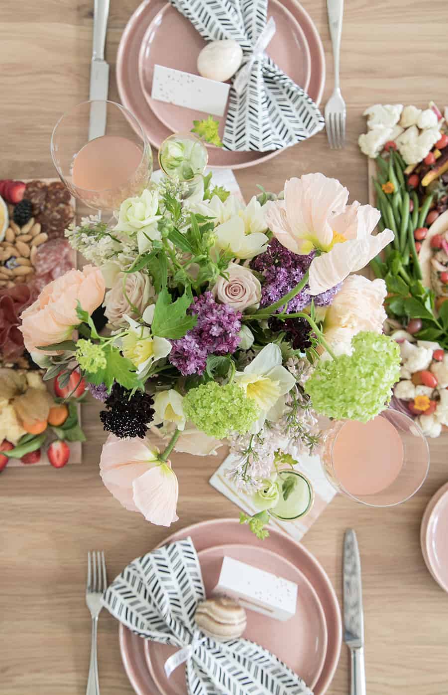 Overhead of flowers on a table with pink plates and Easter eggs.