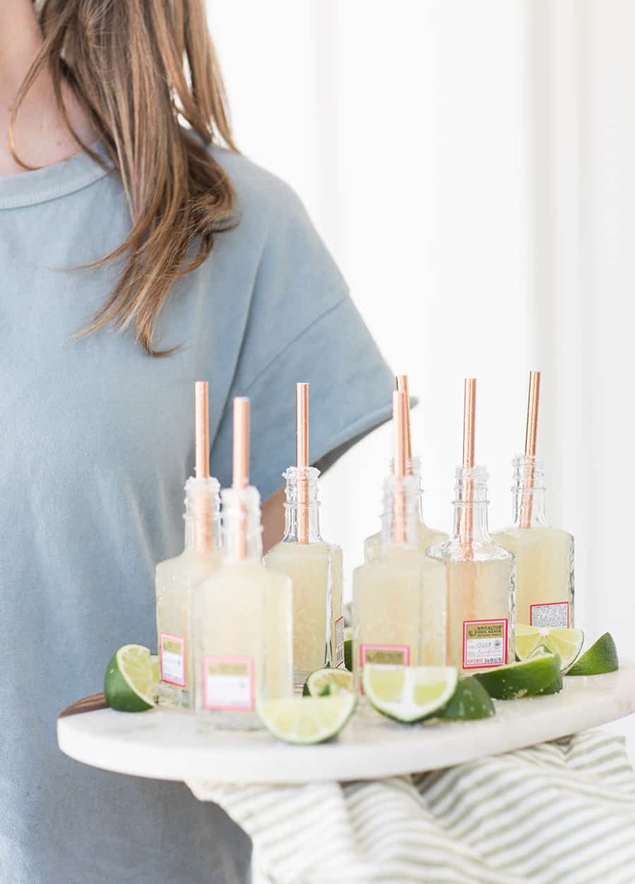 Girl serving mini margaritas in tequila bottles at a party.