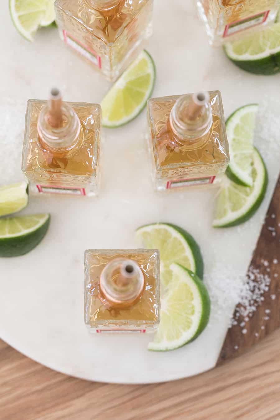 Mini tequila shots on marble platter with lime wedges and salt. - drink margarita, jose cuervo margarita minis