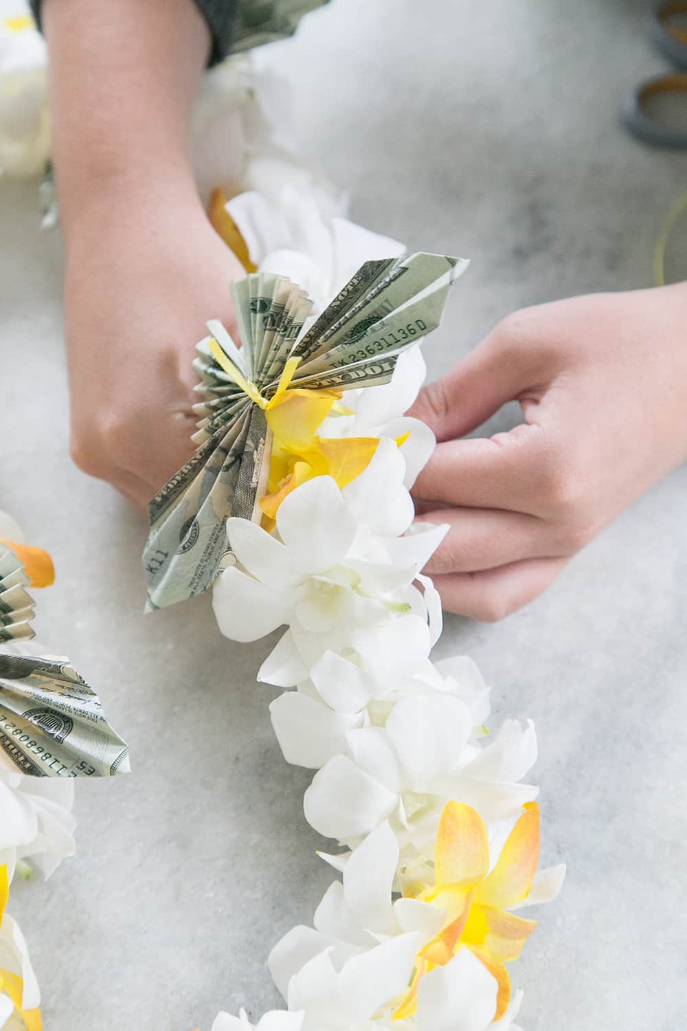 hands putting a money butterfly on a lei