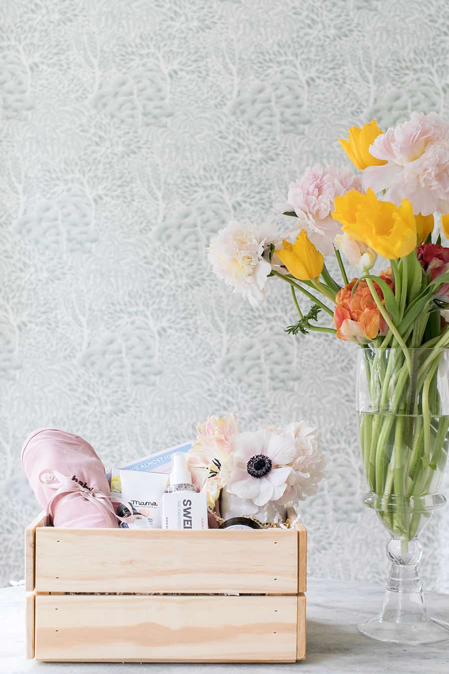 Baby gift basket in a wooden crate with flowers. 