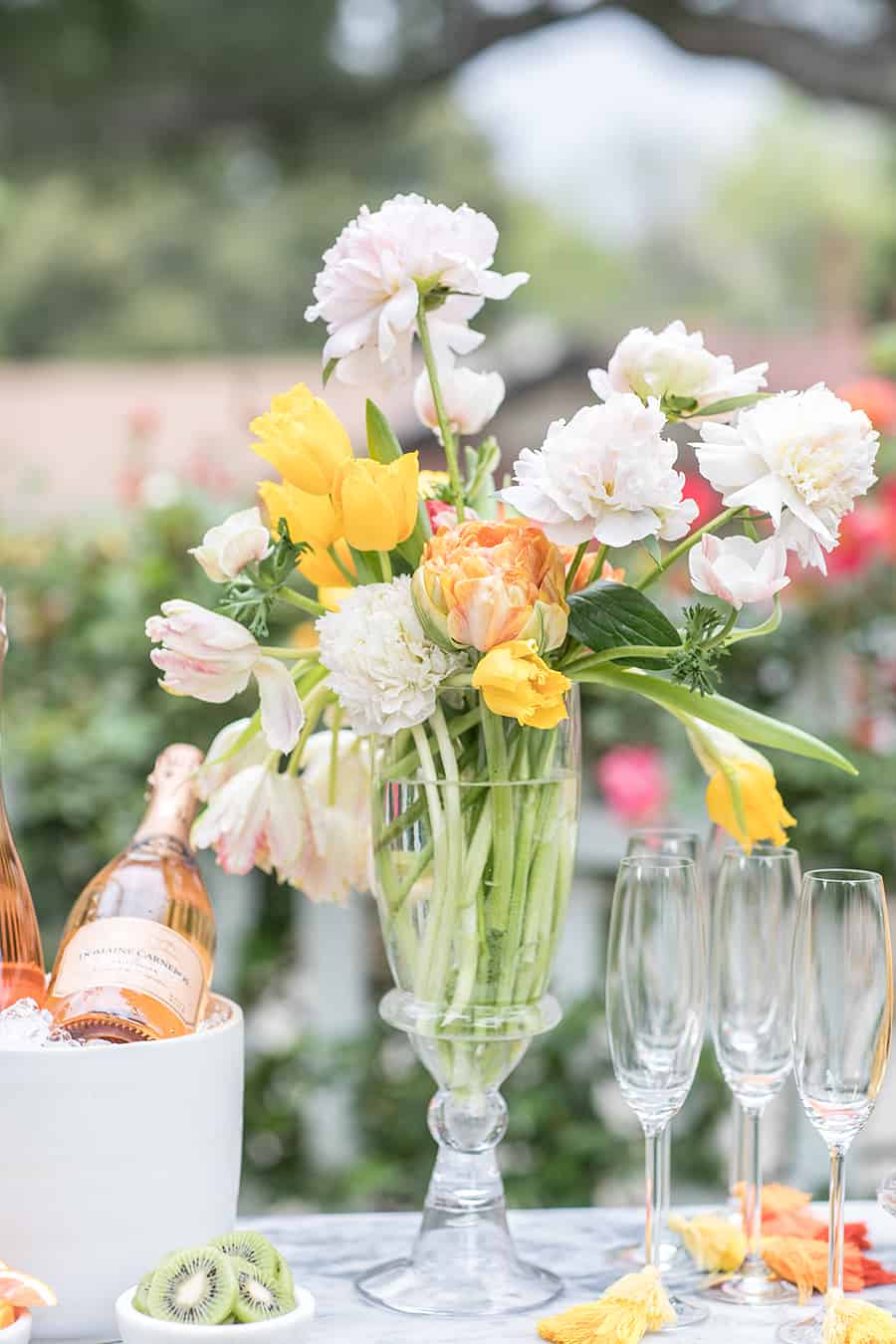 Beautiful flowers in a tall vase with champagne glasses and tassels.