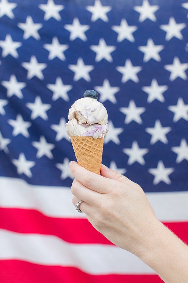 Cheesecake ice cream with blueberries in front of an American flag for the 4th of July.