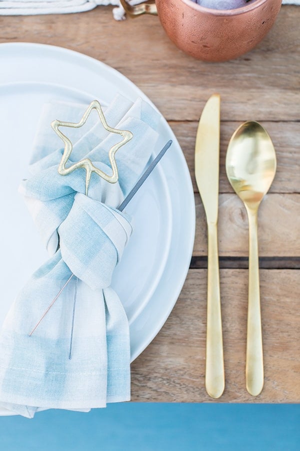 Blue and white napkin, gold flatware with sparkles.