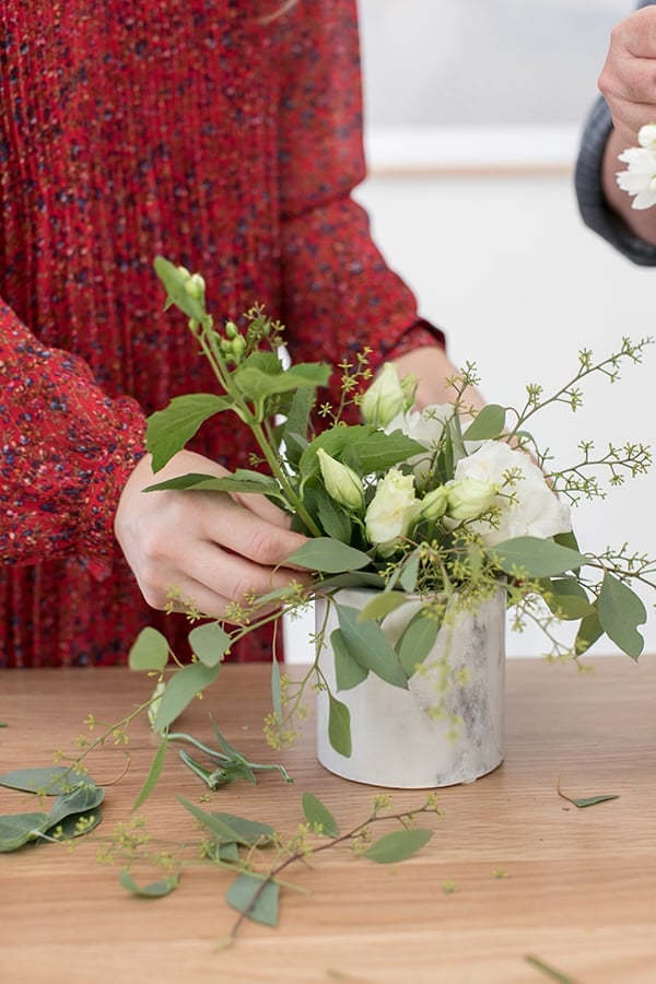 Arranging flowers in a marble vase.