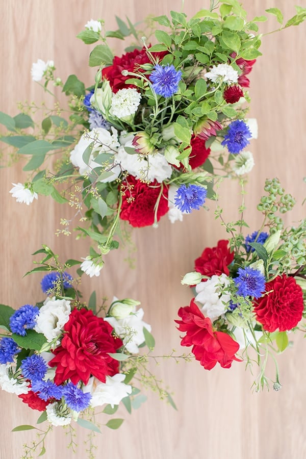 4th of July flowers, red, white and blue on a wood table.