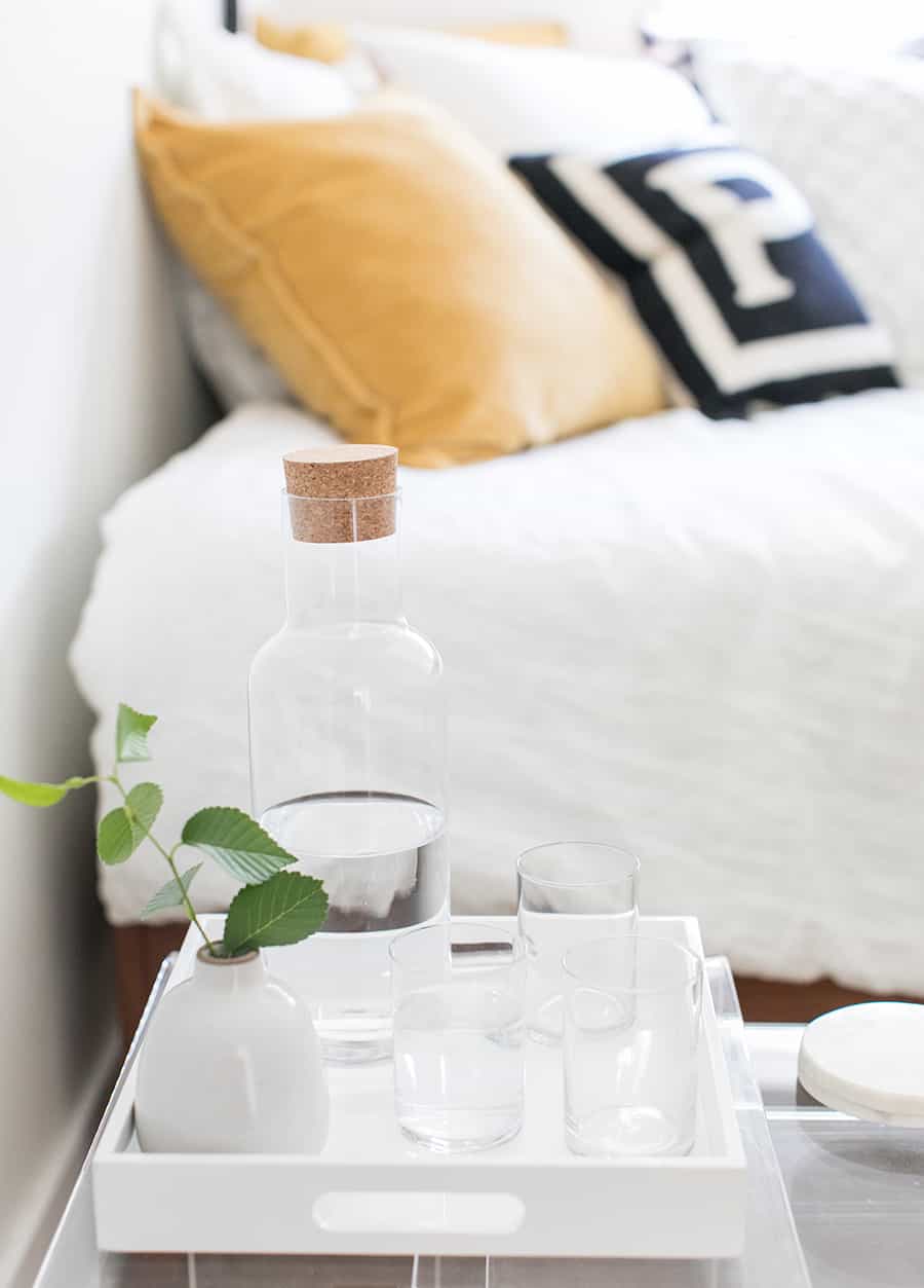 Water and cups next to a bed.