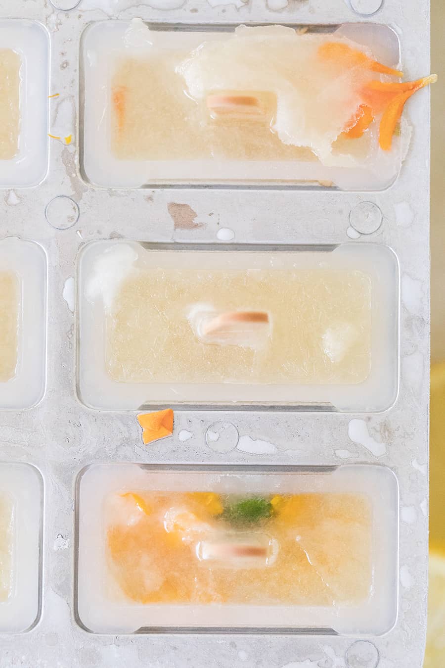 Overhead photo of lemonade popsicles in a popsicle mild with edible flowers.