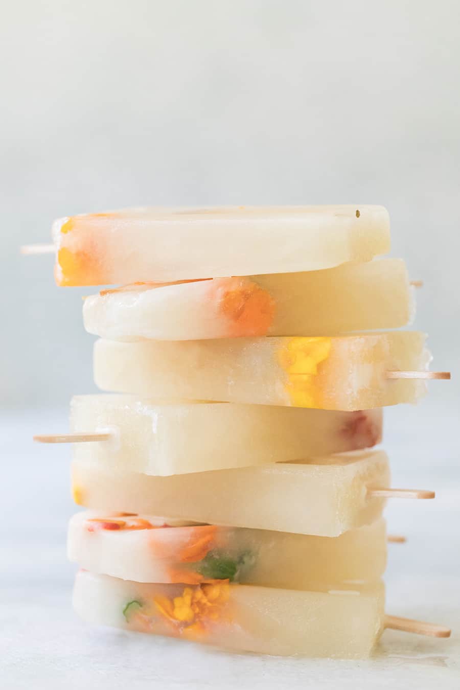 Stack of Three Ingredient Honey Lemonade Popsicles with edible flowers.