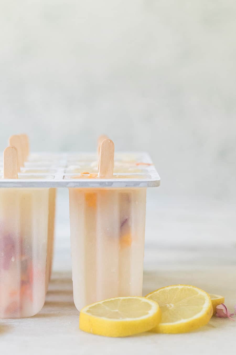 Lemonade popsicles in a popsicle mold with edible flowers. 