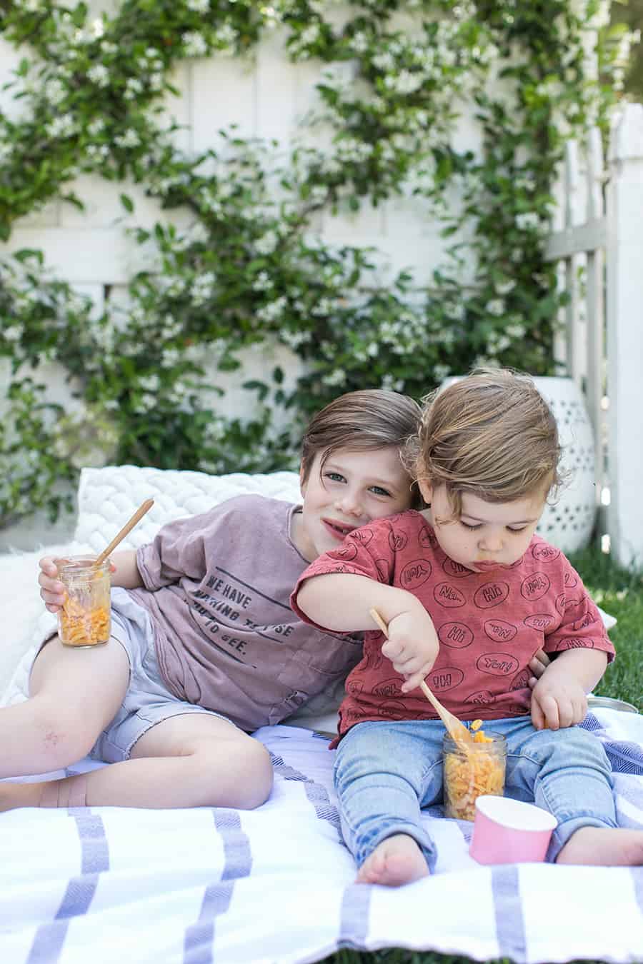 Little kids eating food for kids in a yard.