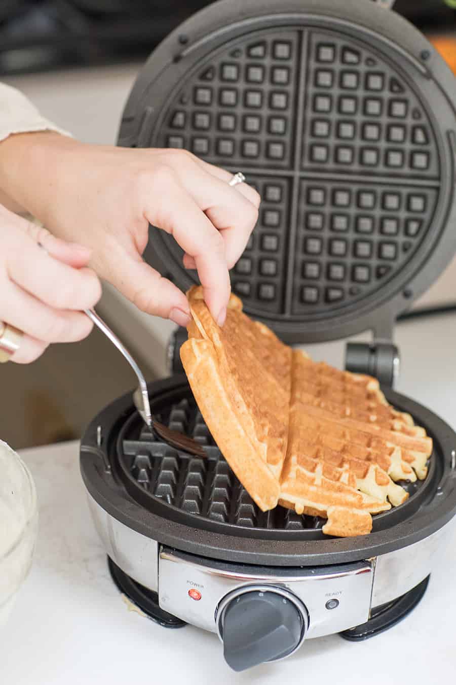 pulling out a cooked homemade waffle recipe from a waffle maker. 