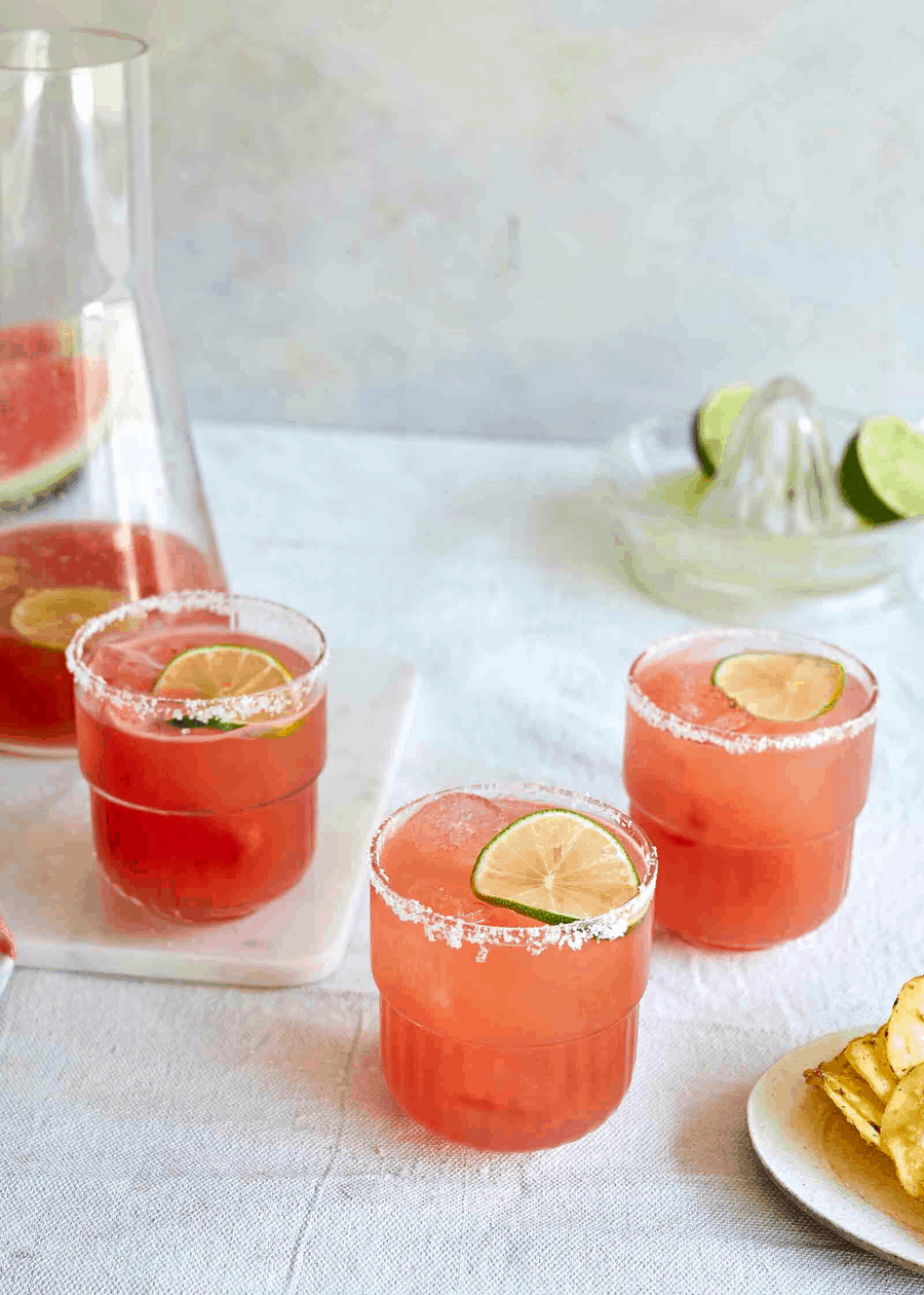 Watermelon margaritas in glasses with slated rim and lime slice,