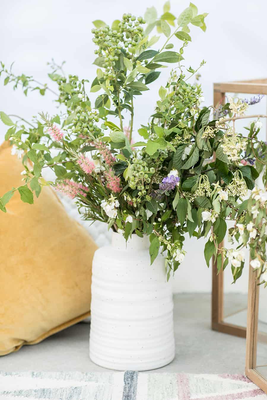 Flowers in white vase and yellow pillows. 