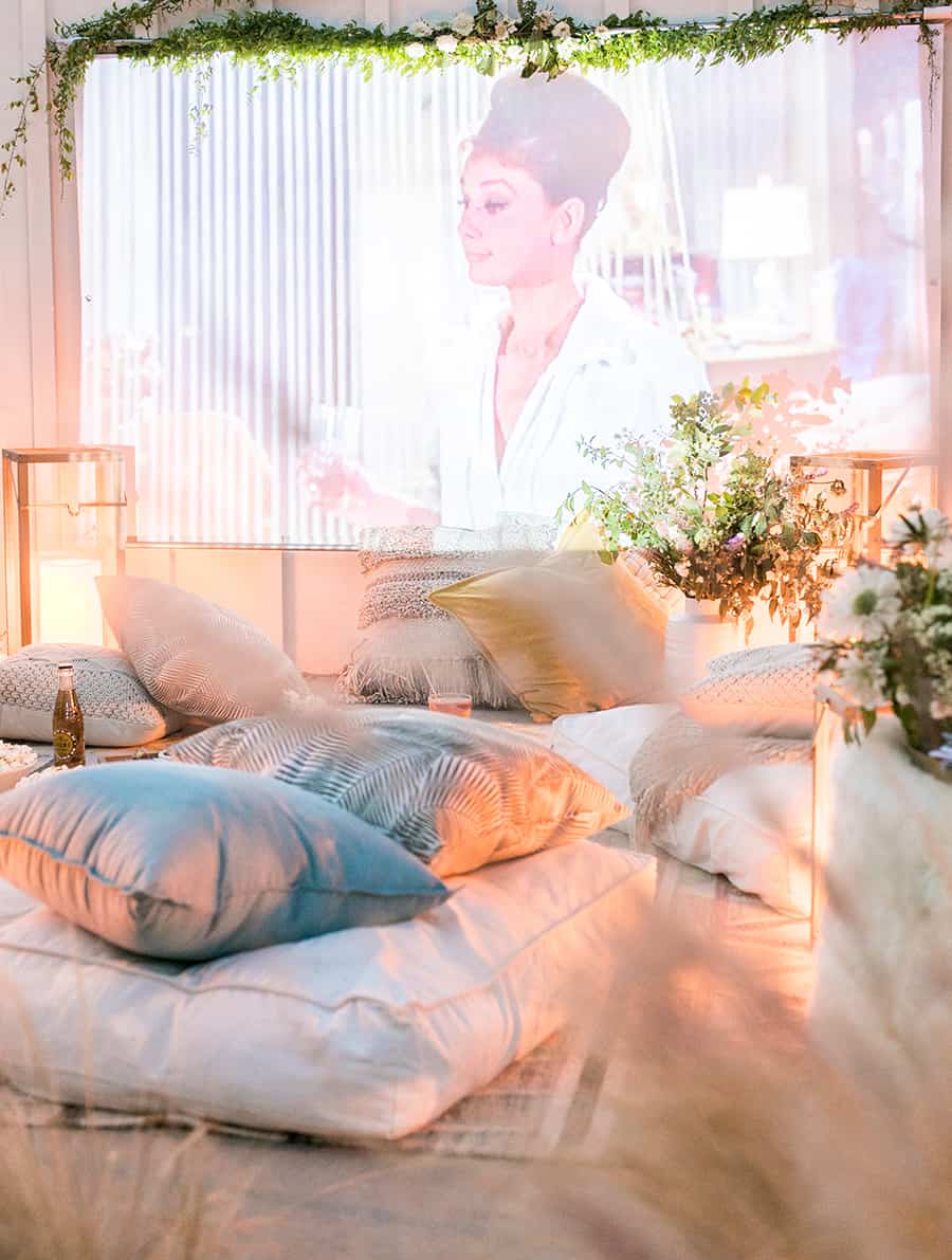 Outdoor movie screen with pillows, lights and flowers 