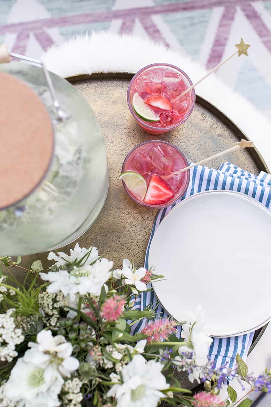 overhead of two red cocktails with plates on gold tray.