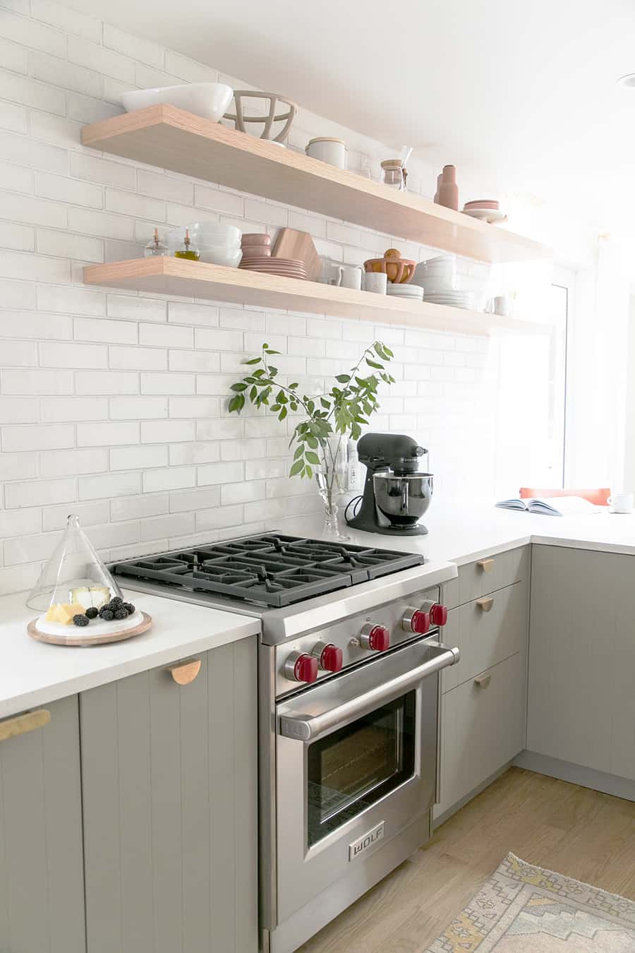 Wolf range with black kitchen aid mixer and green cabinets 