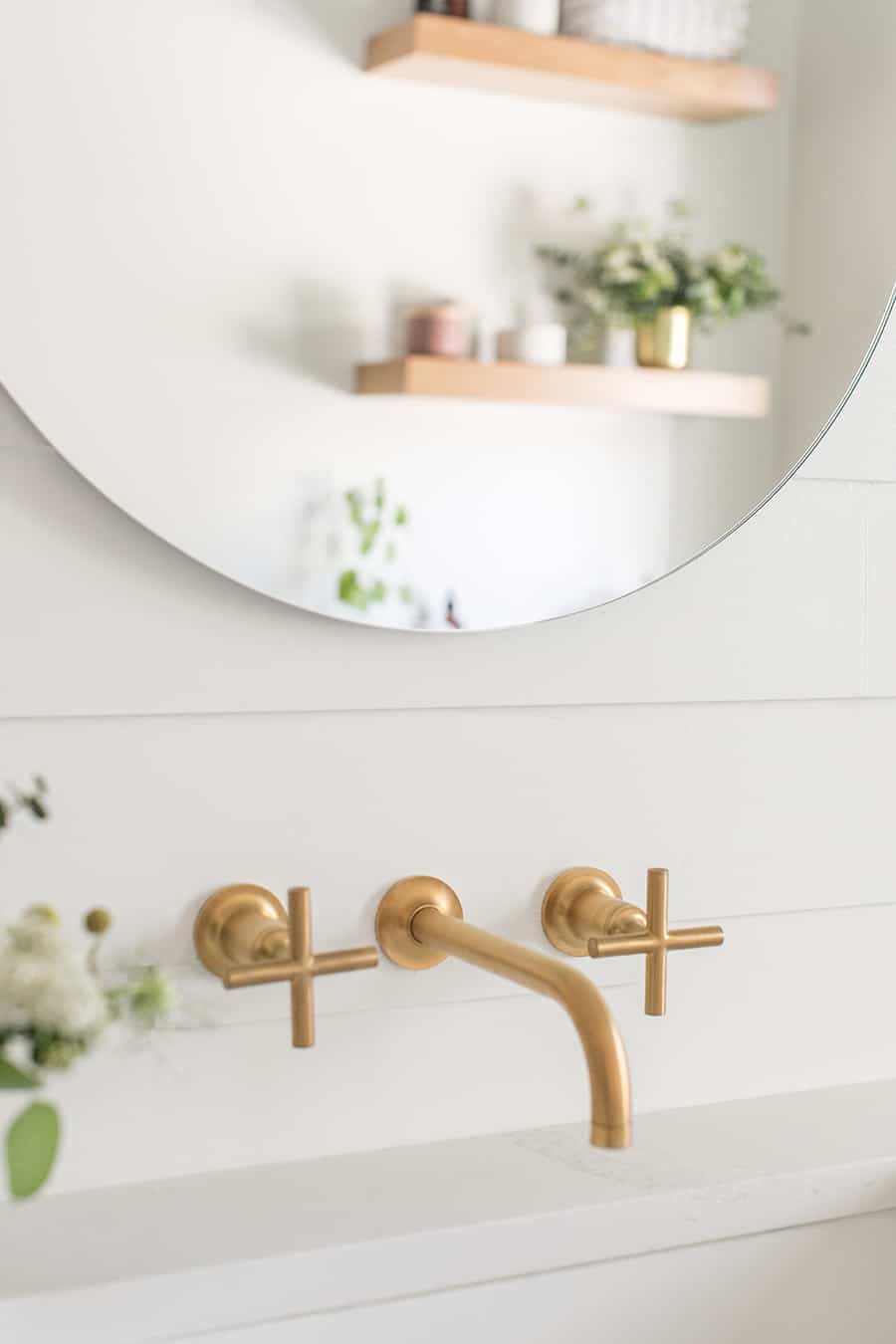 Gold Kohler bathroom faucet with round mirror. small bathroom remodel