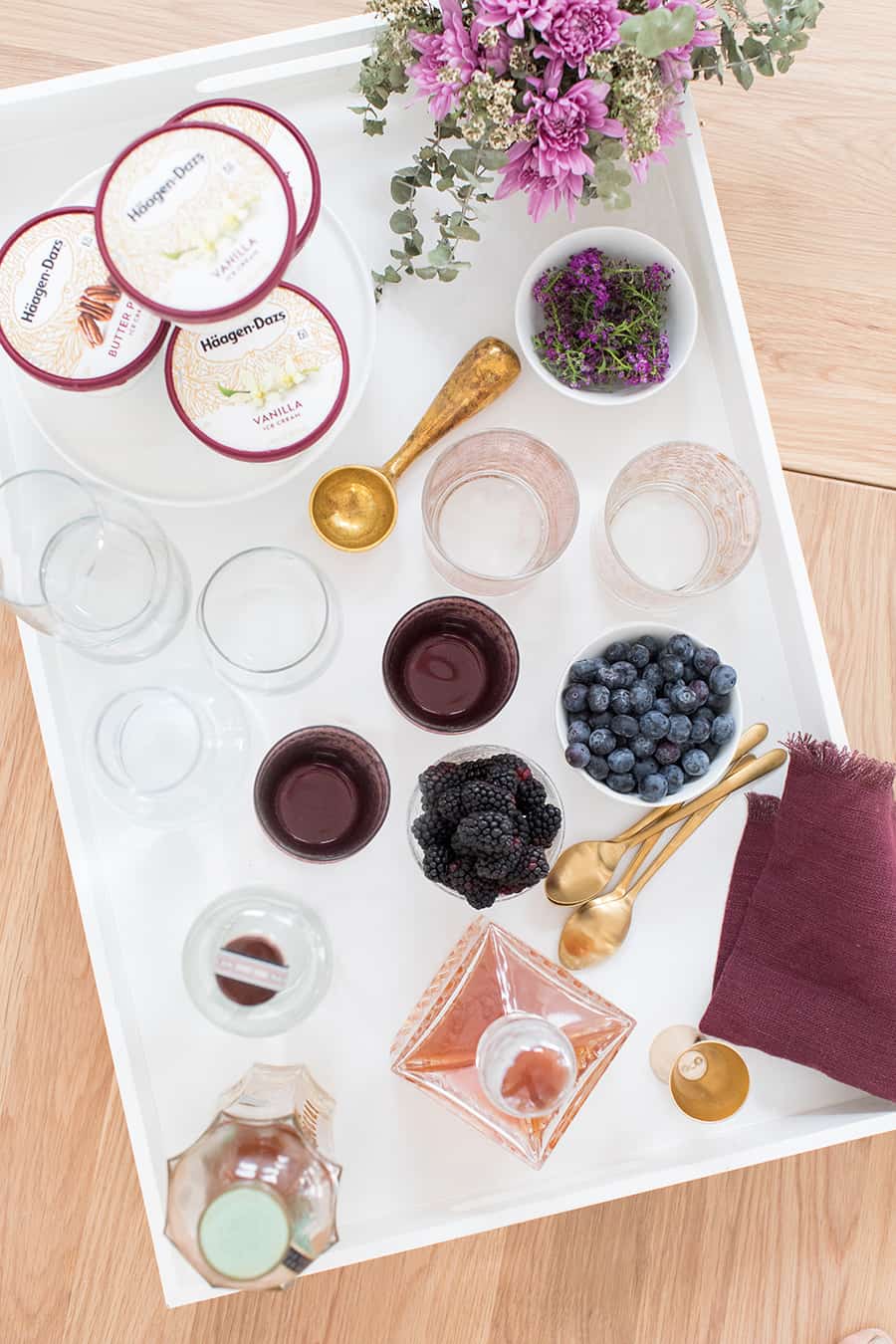 ice cream sundae bar on a white tray with berries and silverware 