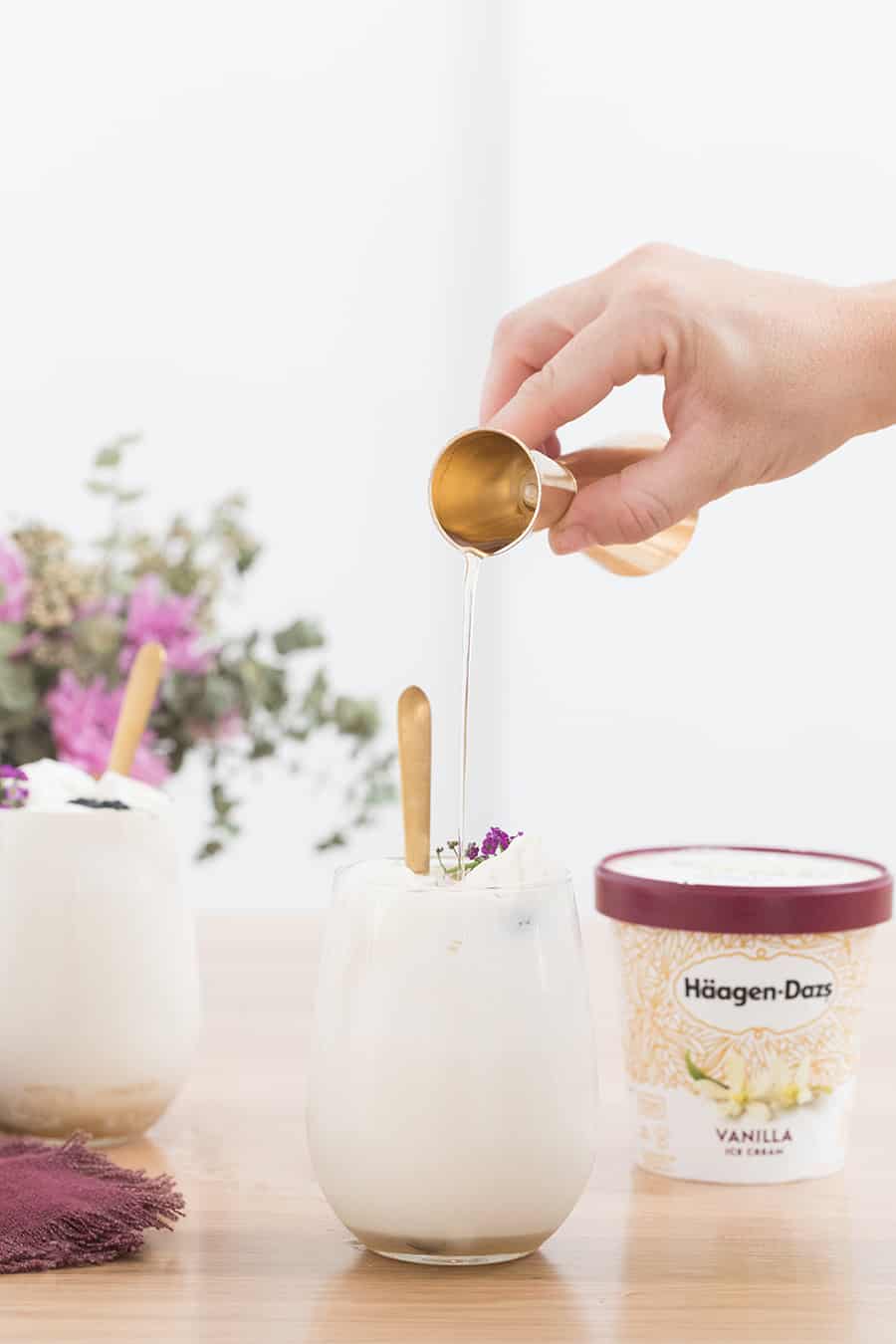 syrup being poured into a glass filled with ice cream 